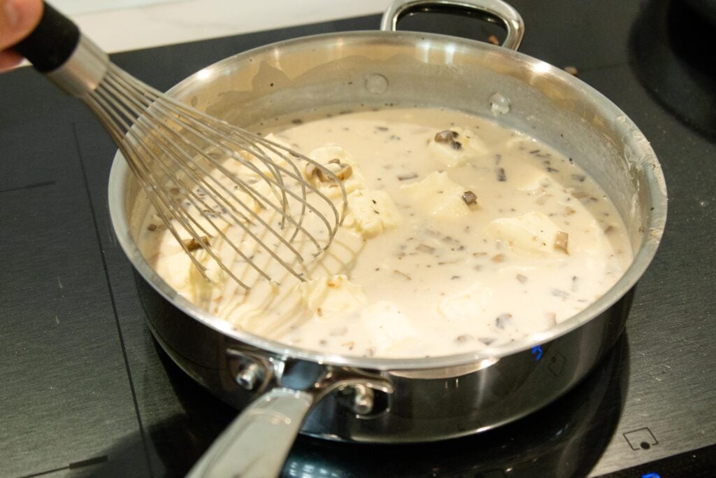 a whisk stirring the mushroom gravy in a pan on the stovetop