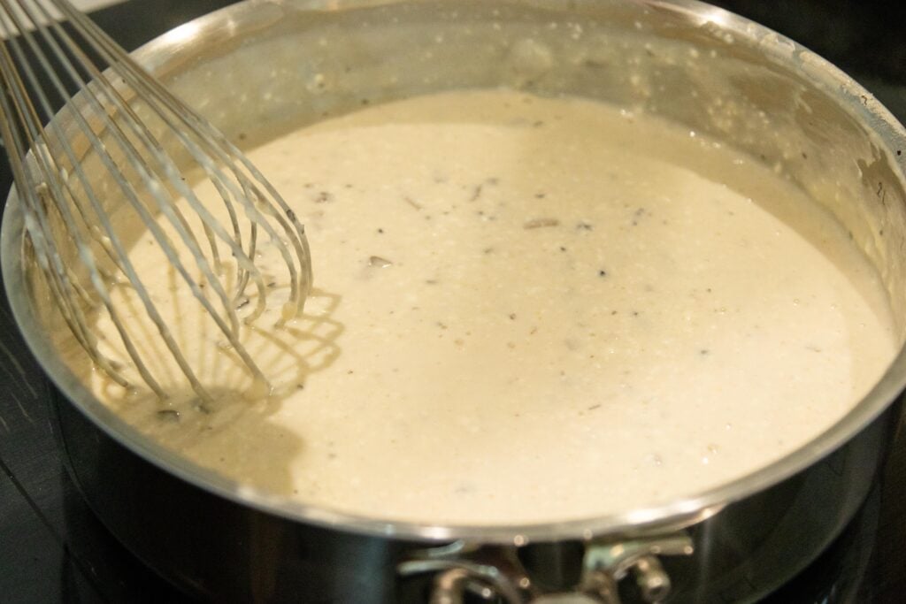 a whisk stirring the mushroom gravy in a pan on the stovetop