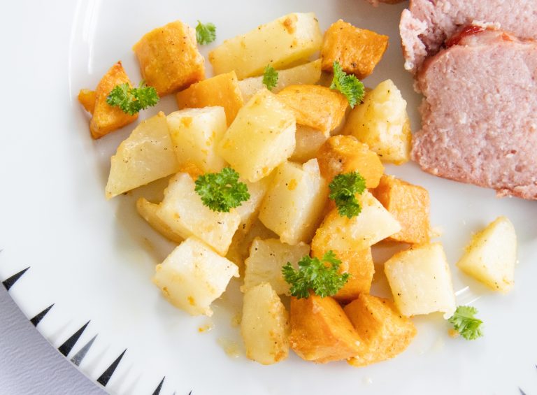 oven roasted parmesan potatoes on a white plate with some ham loaf