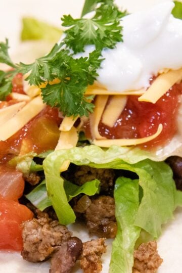 tortilla shell with taco meat and a bunch of toppings