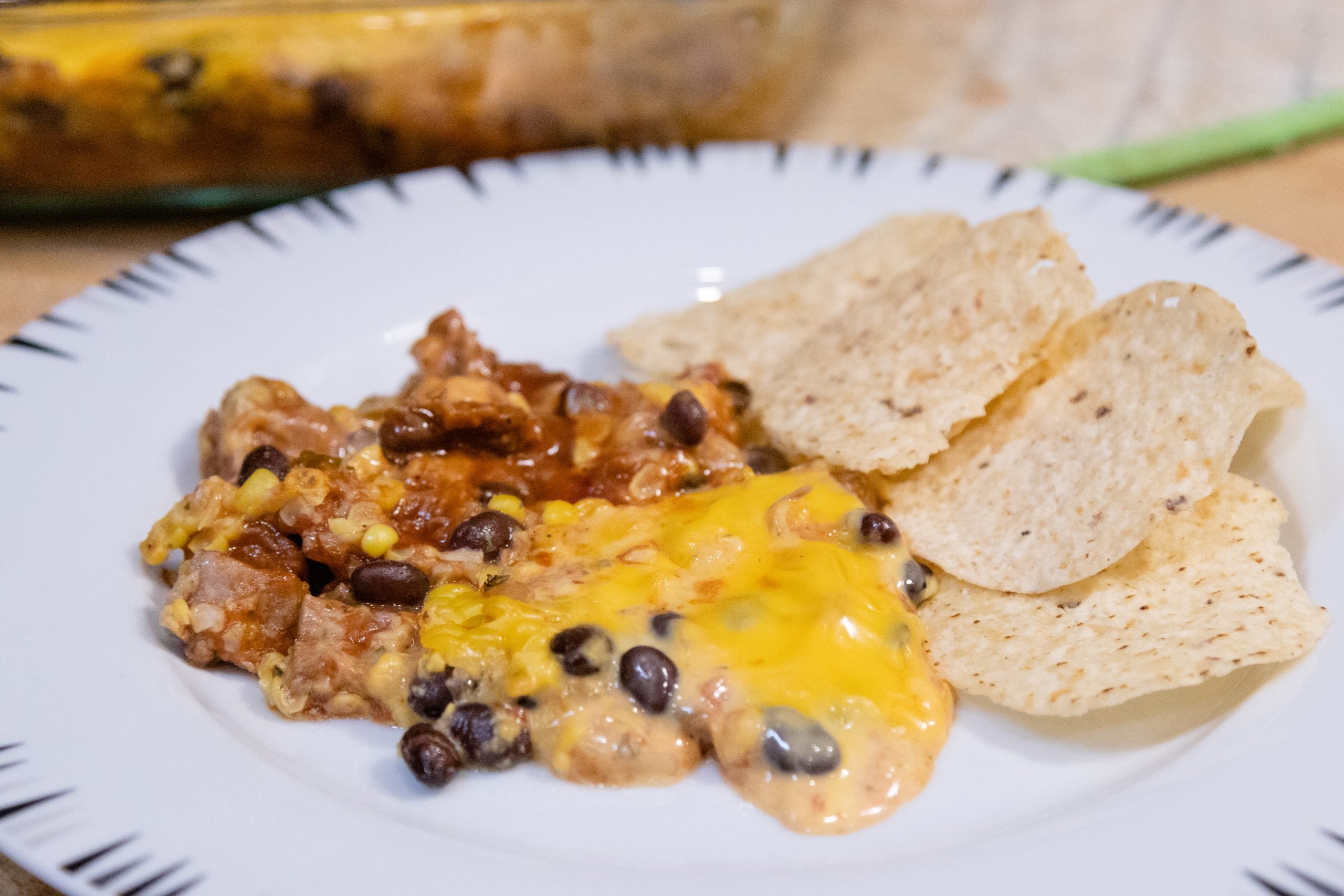 white plate with nacho dip and tortilla chips on it