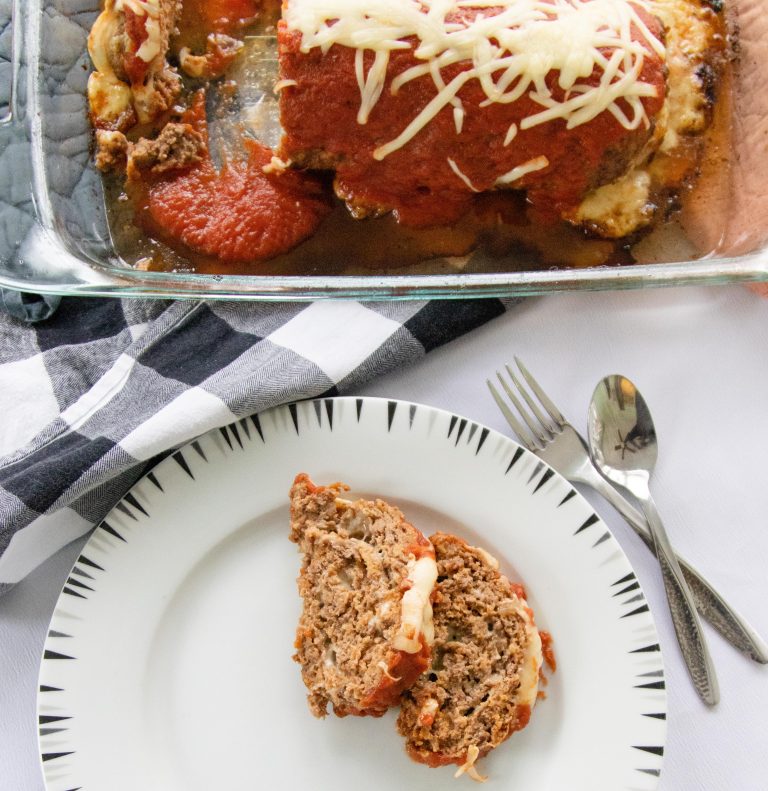 plate with 2 slices of meatloaf beside a glass pan with meatloaf cheese roll inside