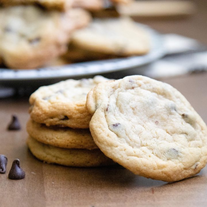 stack of three chocolate chip cookies with a fourth one propped up against