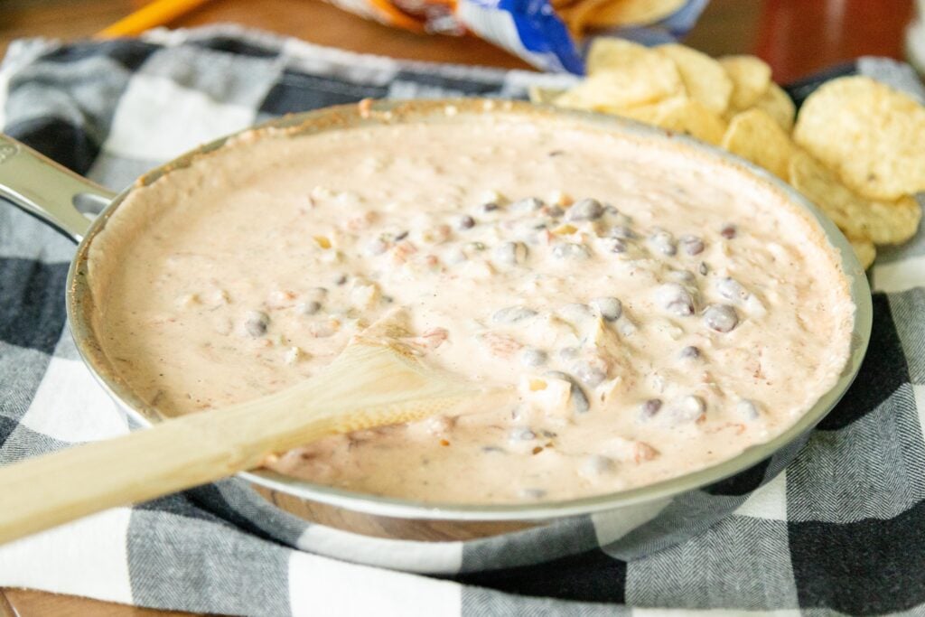 creamy salsa bean dip on the table beside a bag of tortilla chips