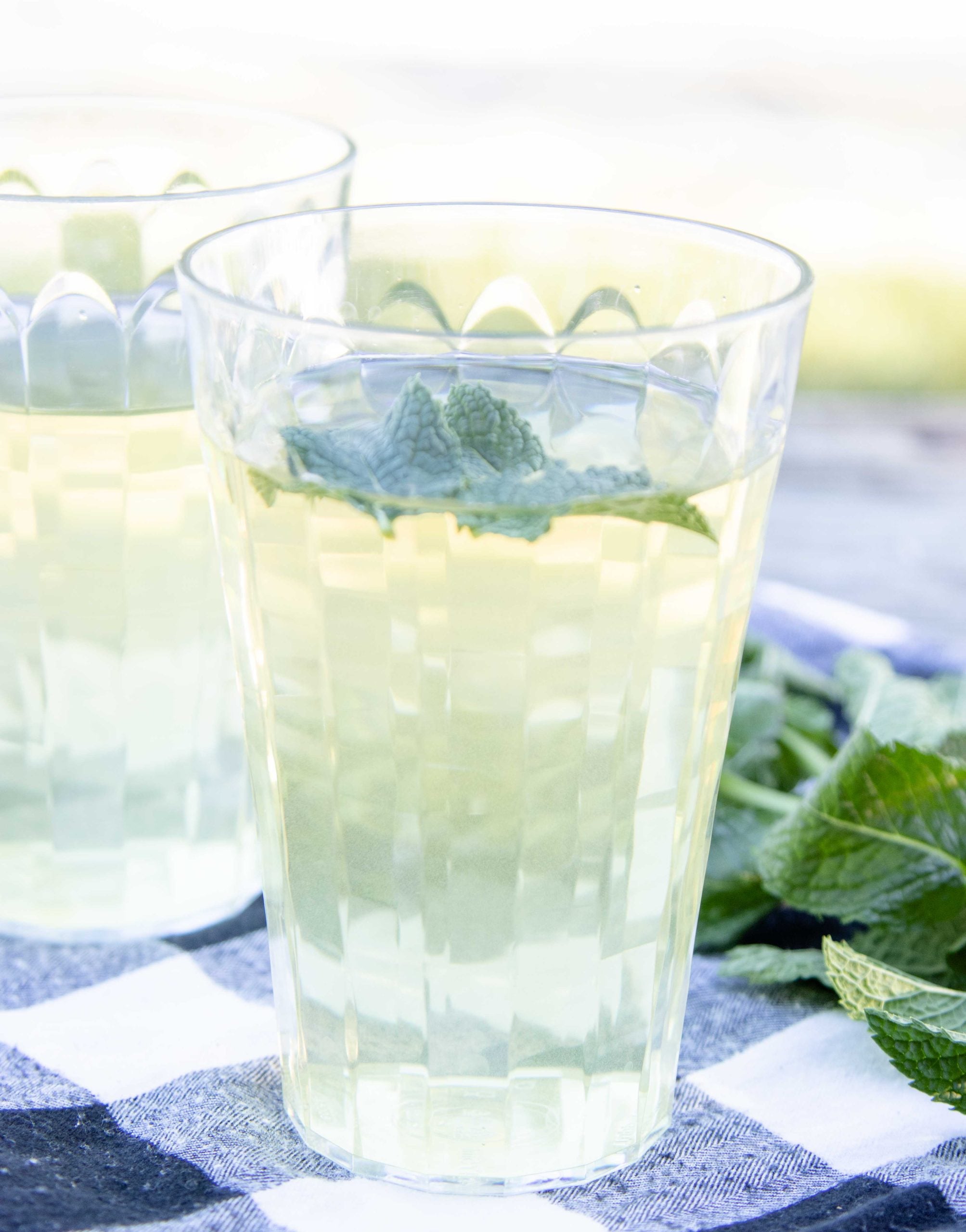 2 glasses of mint meadow tea with the pitcher of tea behind