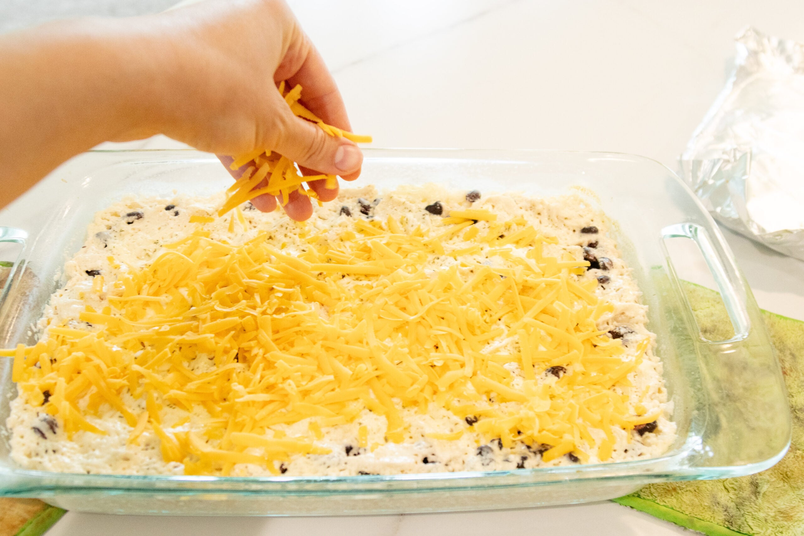 sprinkling the cheese on top of the casserole