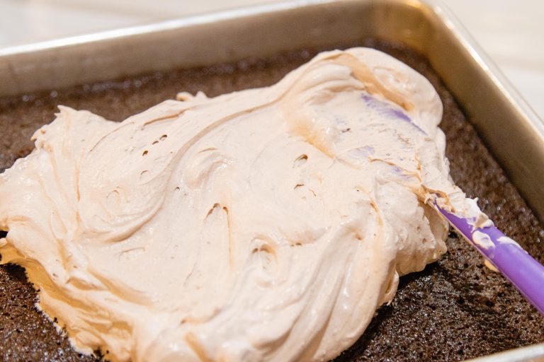 spreading the pudding frosting on a cake with a spatula