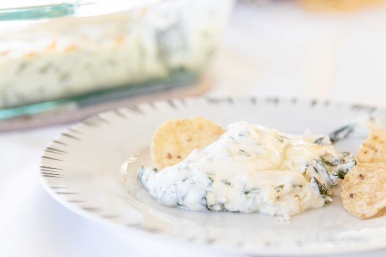 serving of classic spinach dip on a plate with some tortilla chips
