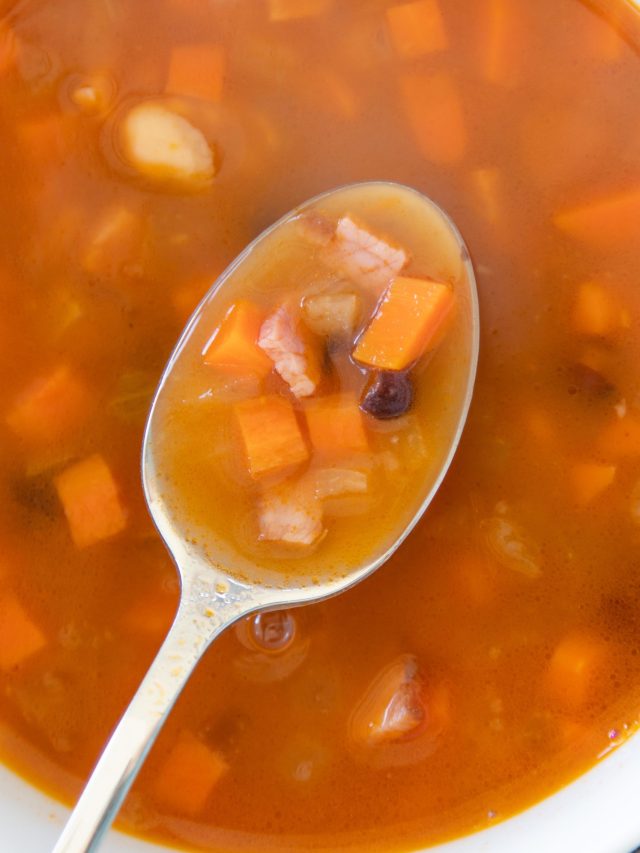 spoon scooping a bite of soup out of a white soup bowl