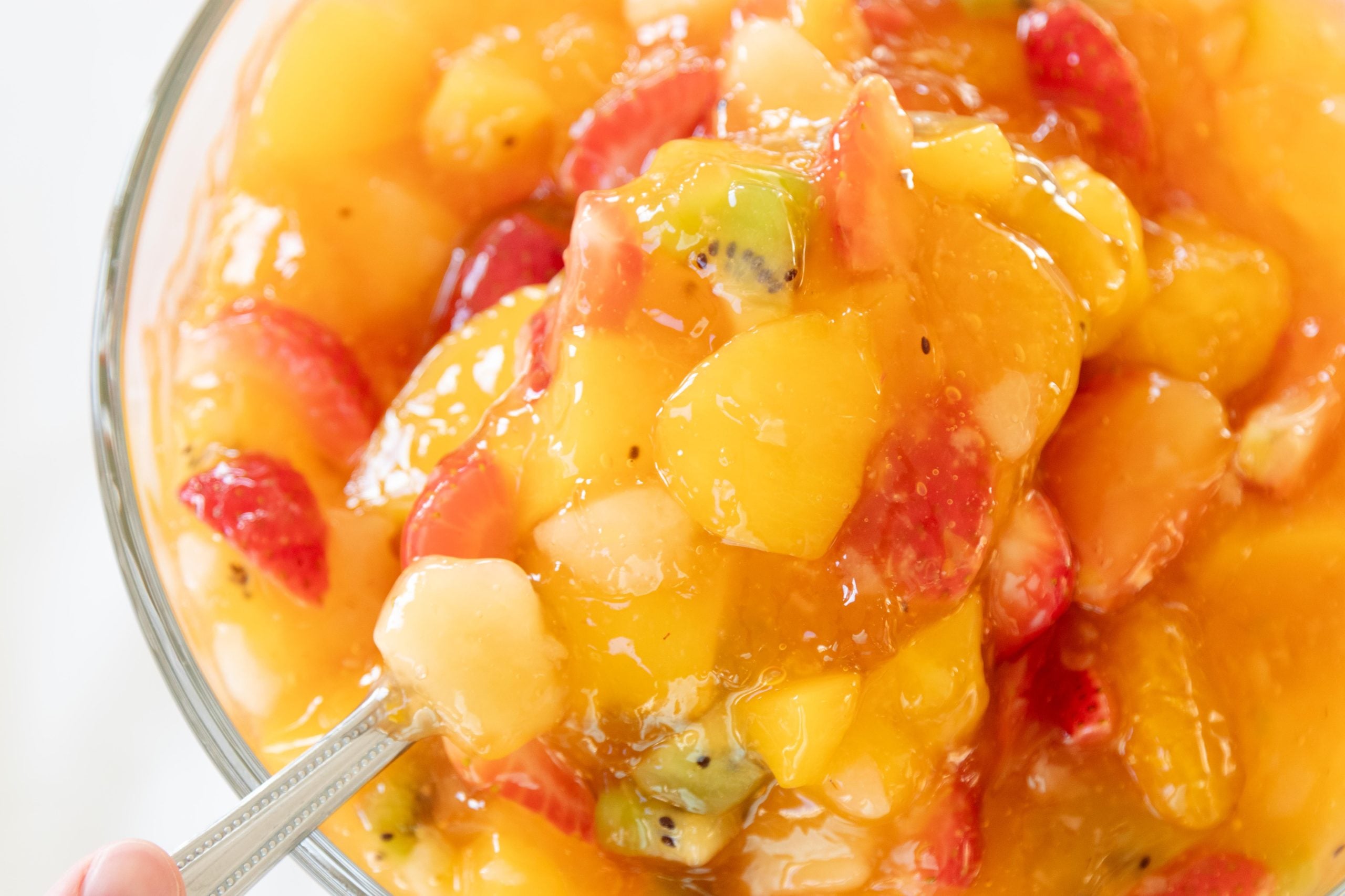 a spoon scooping out a helping of thickened fruit salad dessert