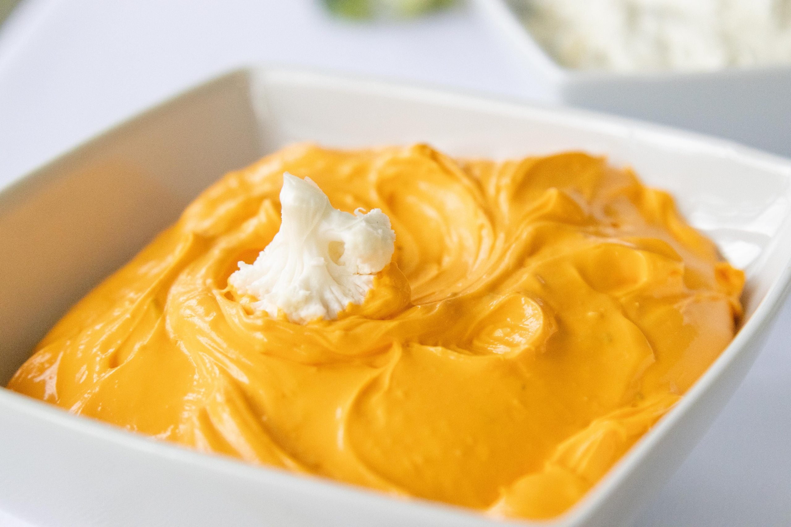 dipping a cauliflower floret in cheddar sour cream dip