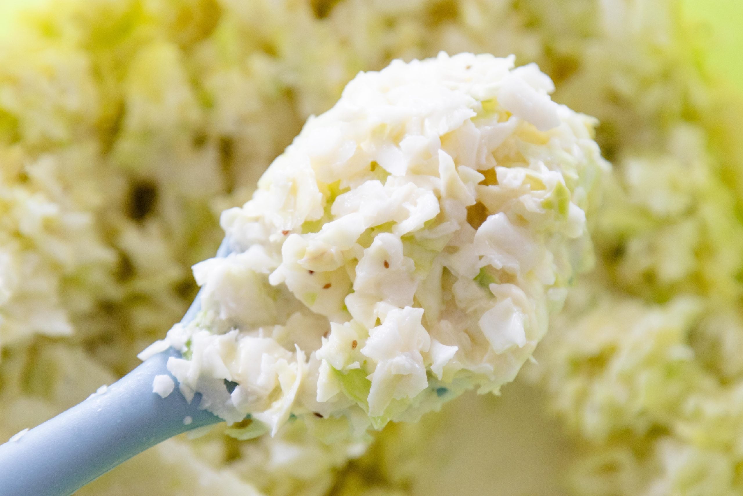 spoon scooping a serving of coleslaw from the dish