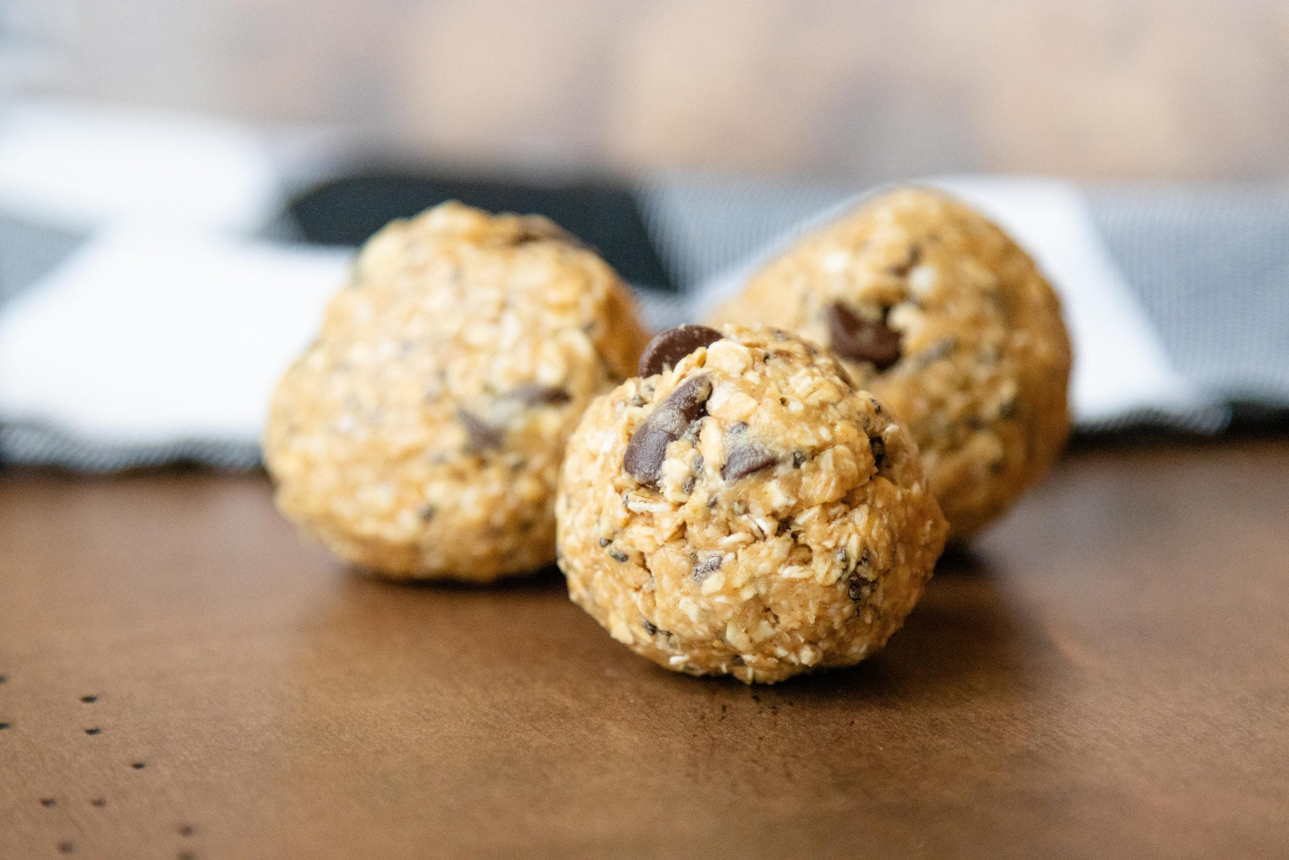three no-bake peanut butter oatmeal balls setting on a brown surface