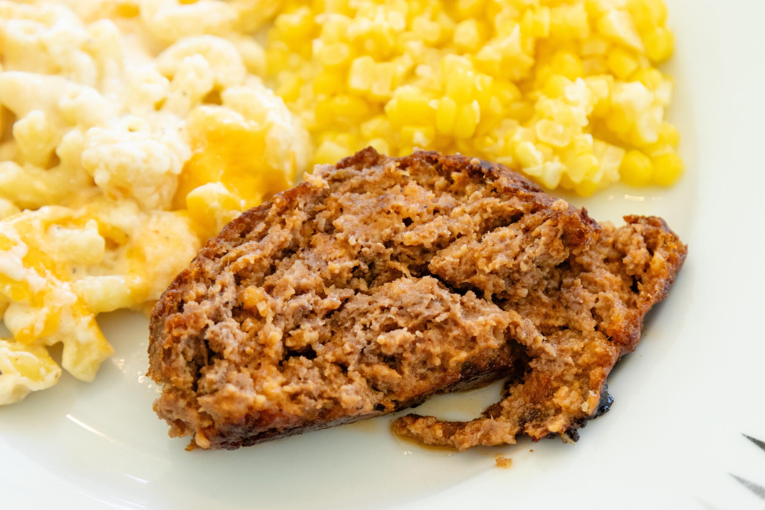a serving of meatloaf on a plate with corn and mac and cheese