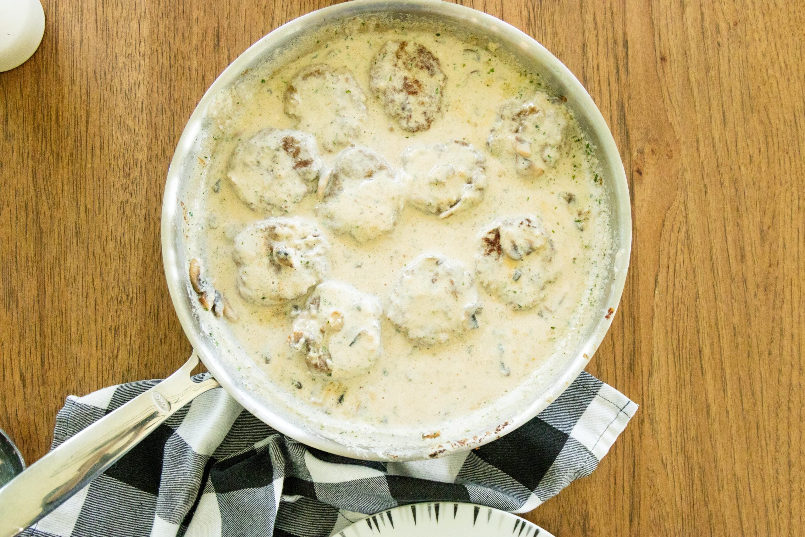 poor mans steaks and mushroom gravy in a frying pan on the table