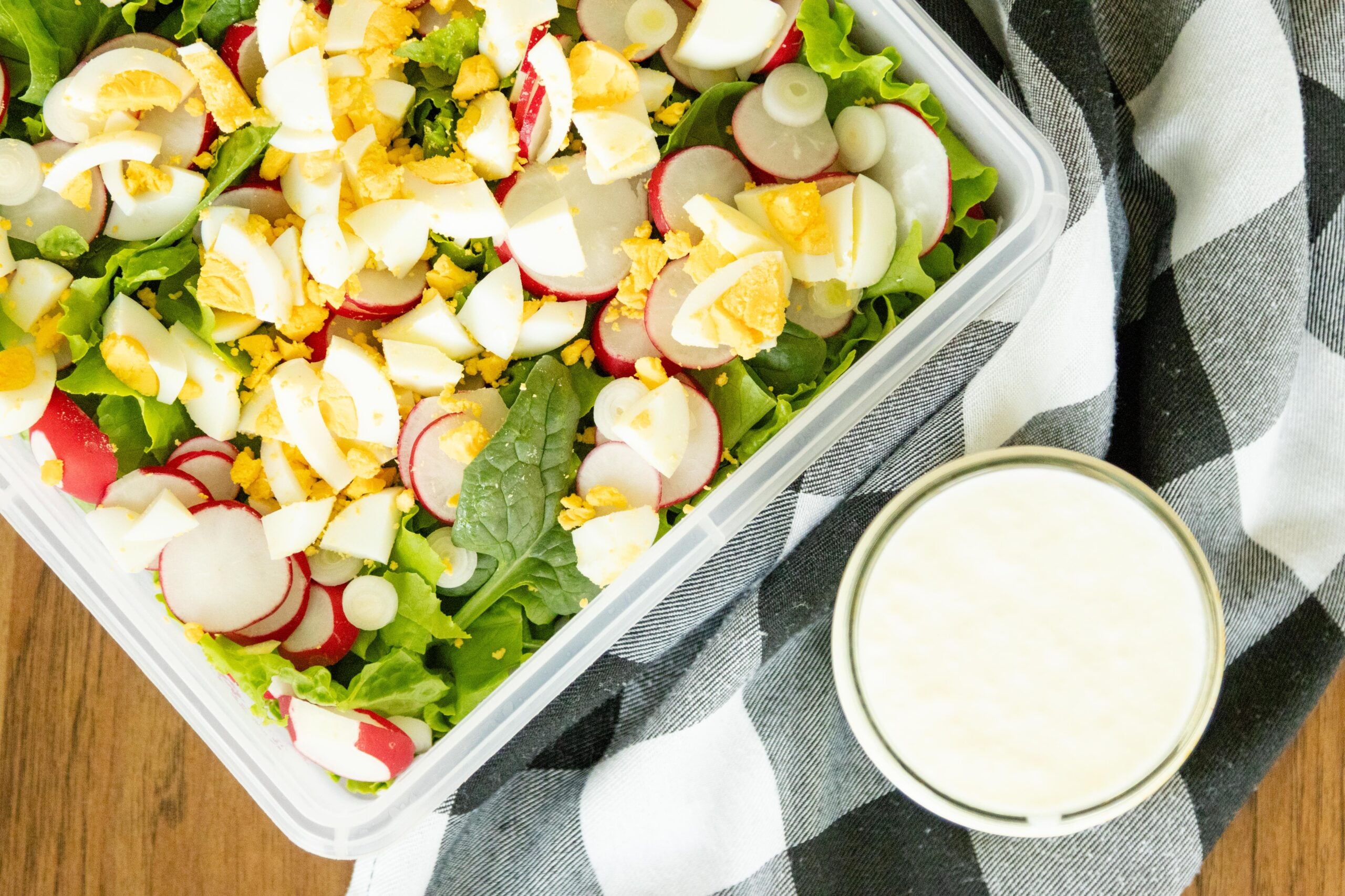 spring garden lettuce salad in a square dish beside a jar of sweet cream dressing