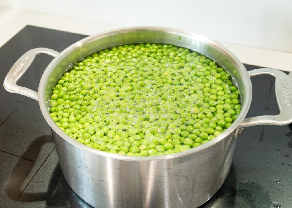 peas cooking in a pot of water on the stovetop