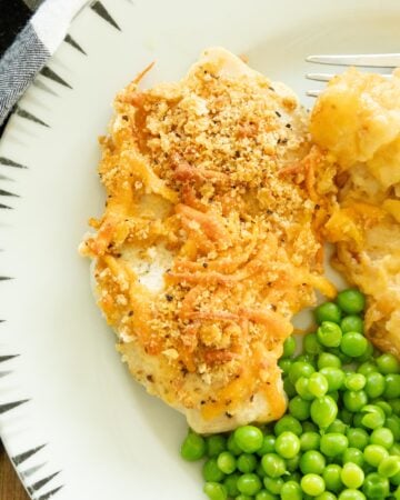 one cheddar ranch chicken breast on a plate with peas and potatoes