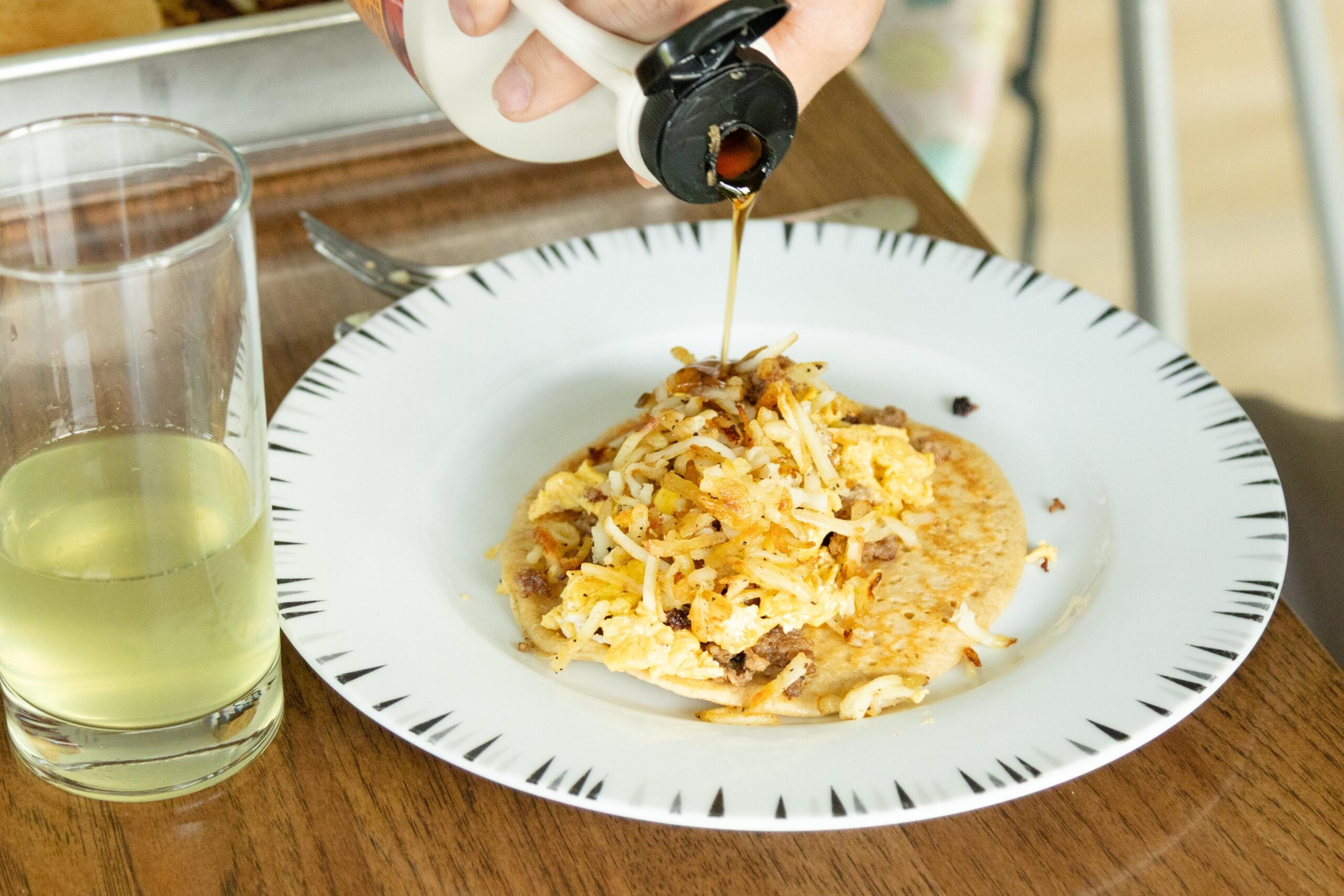drizzling maple syrup onto a pancake breakfast taco