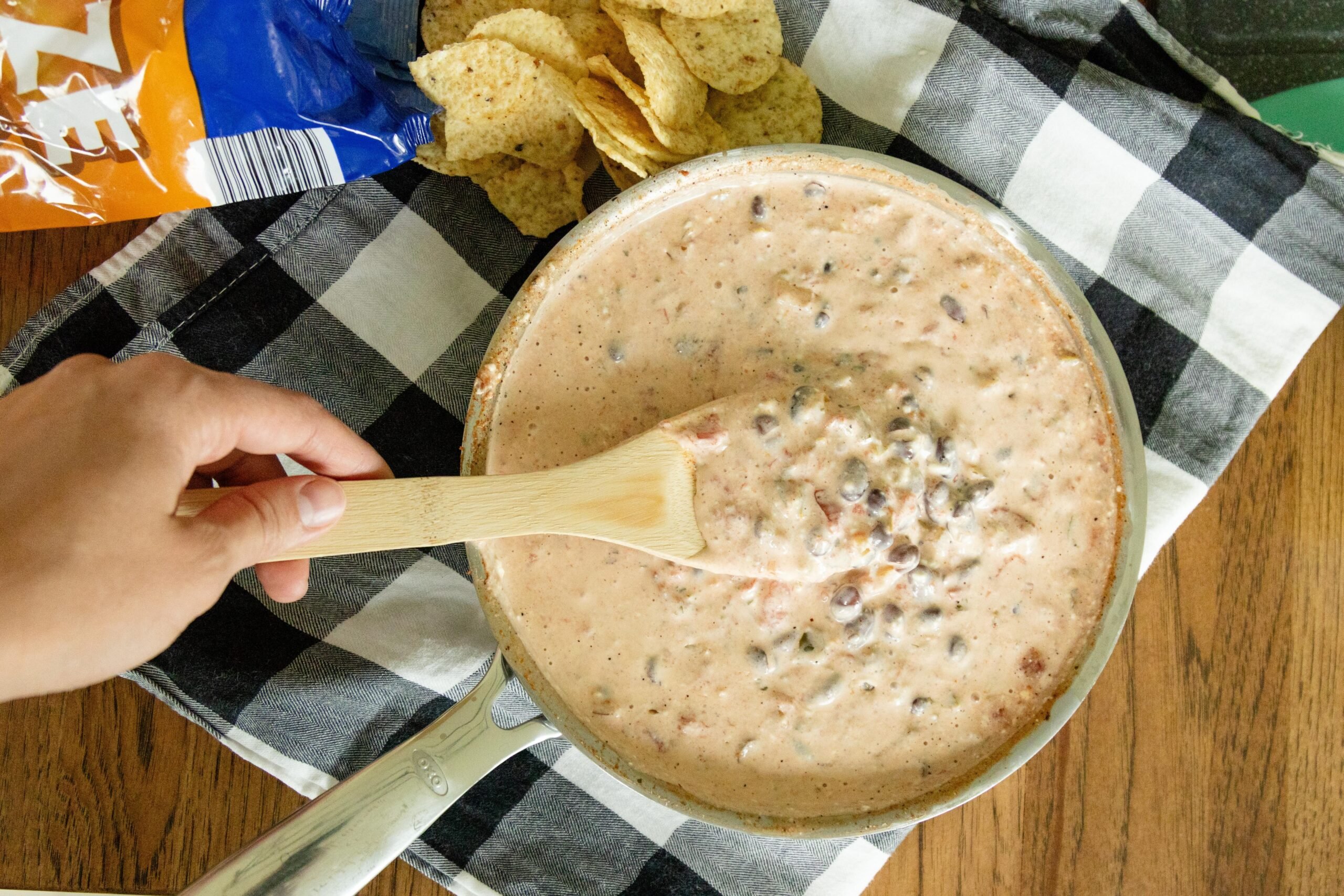 creamy salsa bean dip in a pan on the table beside a bag of tortilla chips