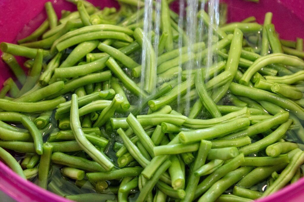 green beans rinsing under the faucet in the sink