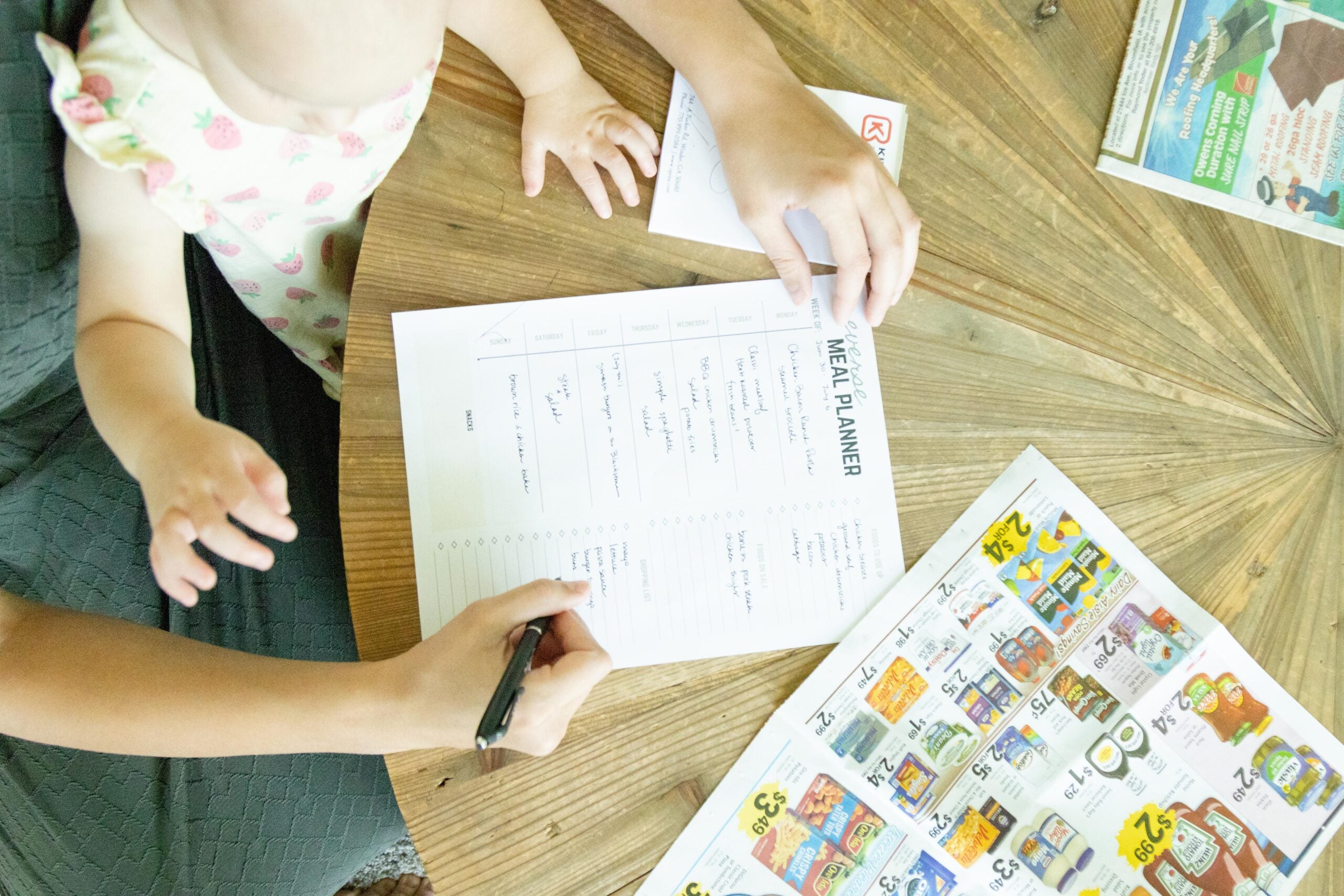 hand writing on the reverse meal plan with a baby standing nearby