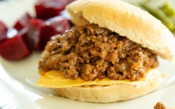 a sloppy joe sandwich on a plate with red beets and green beans