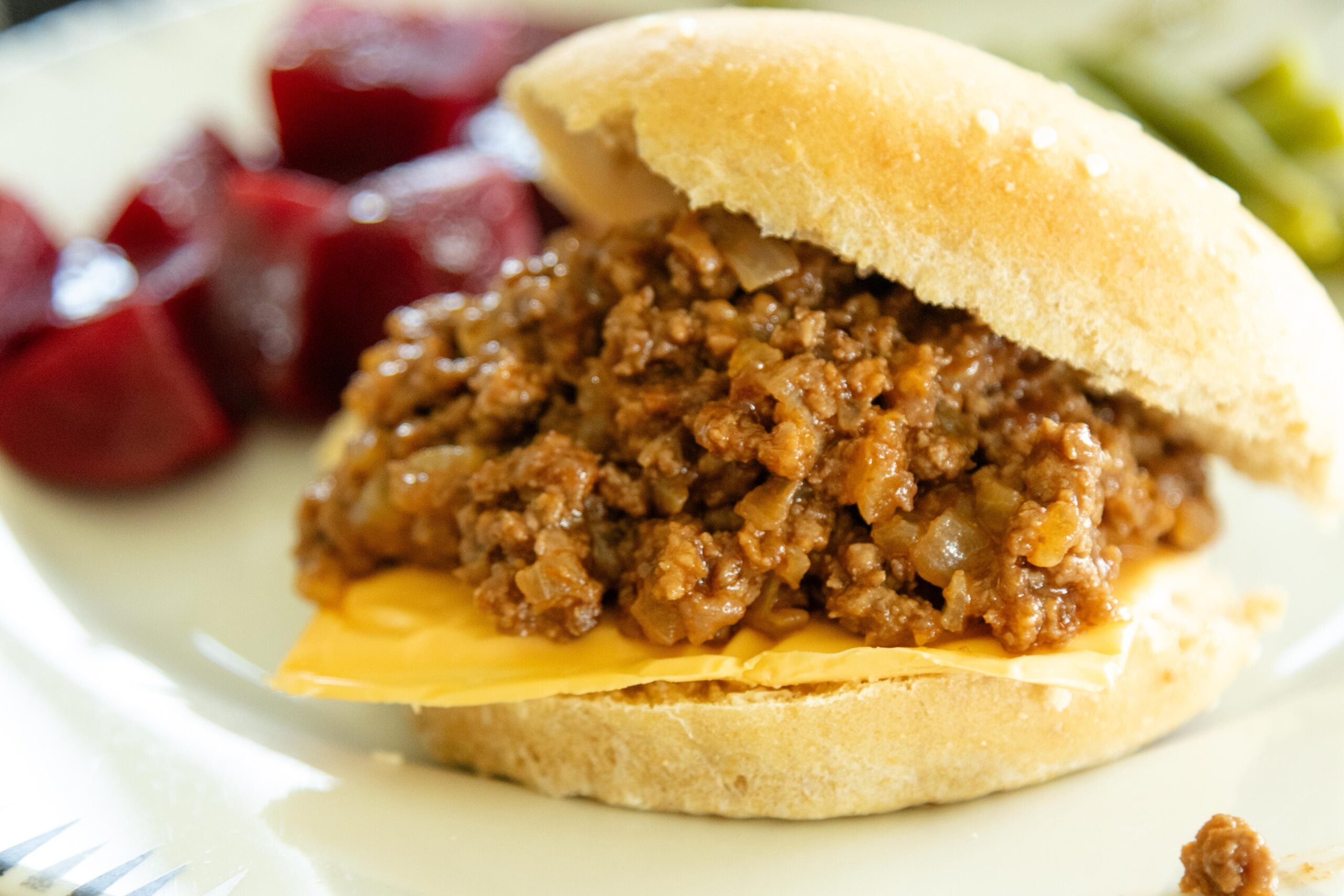 a sloppy joe sandwich on a plate with red beets and green beans