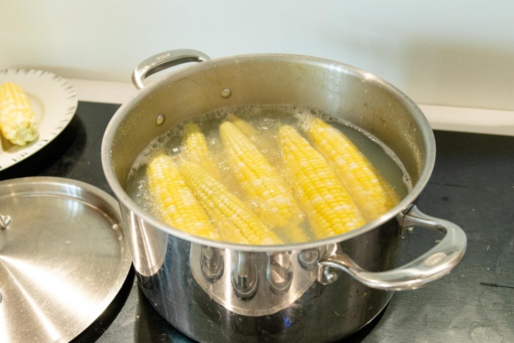 corn cobs boiling in a pot of water