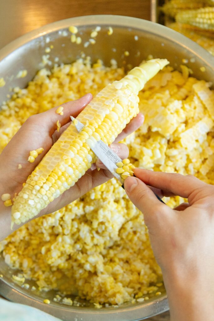 cutting the corn from the cob into a dish