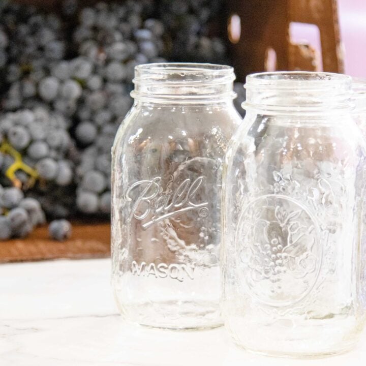 a box of grapes setting beside some canning jars