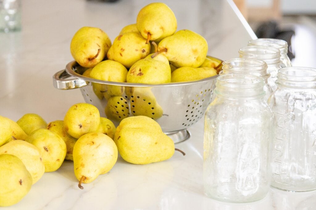 pears in a colander with empty jars setting nearby