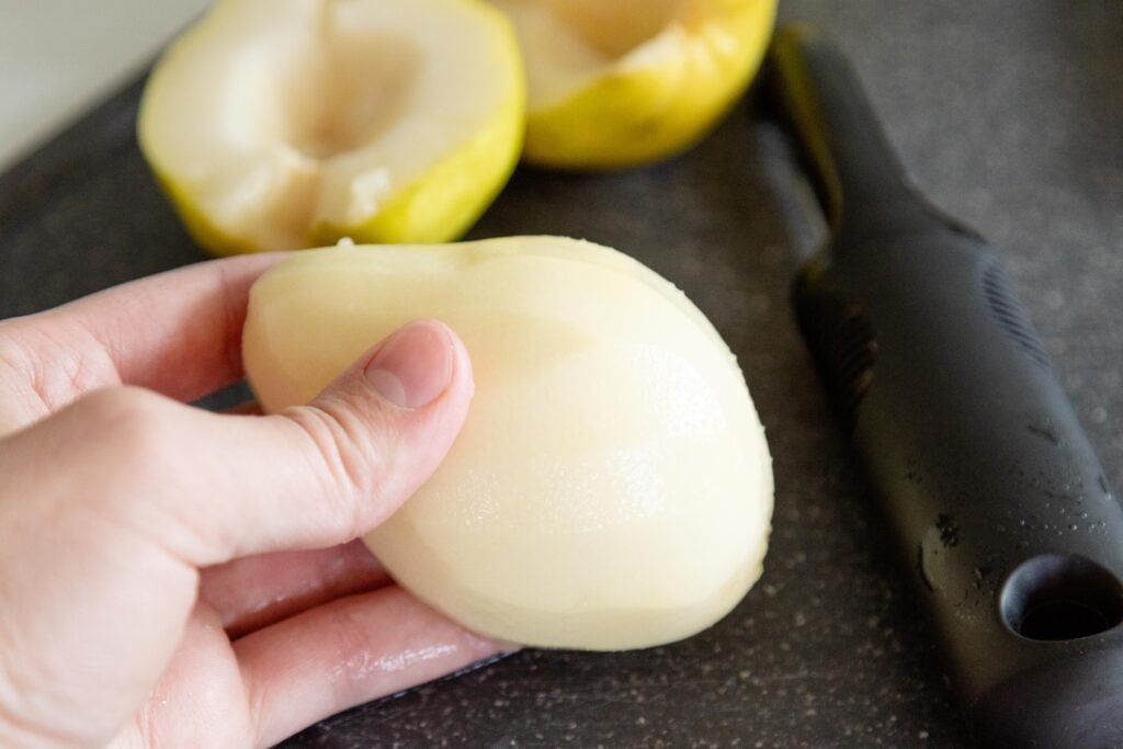 hand holding a peeled pear half