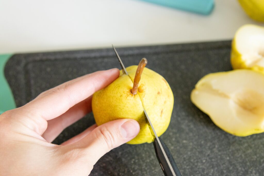 cutting a pear in half on a cutting board