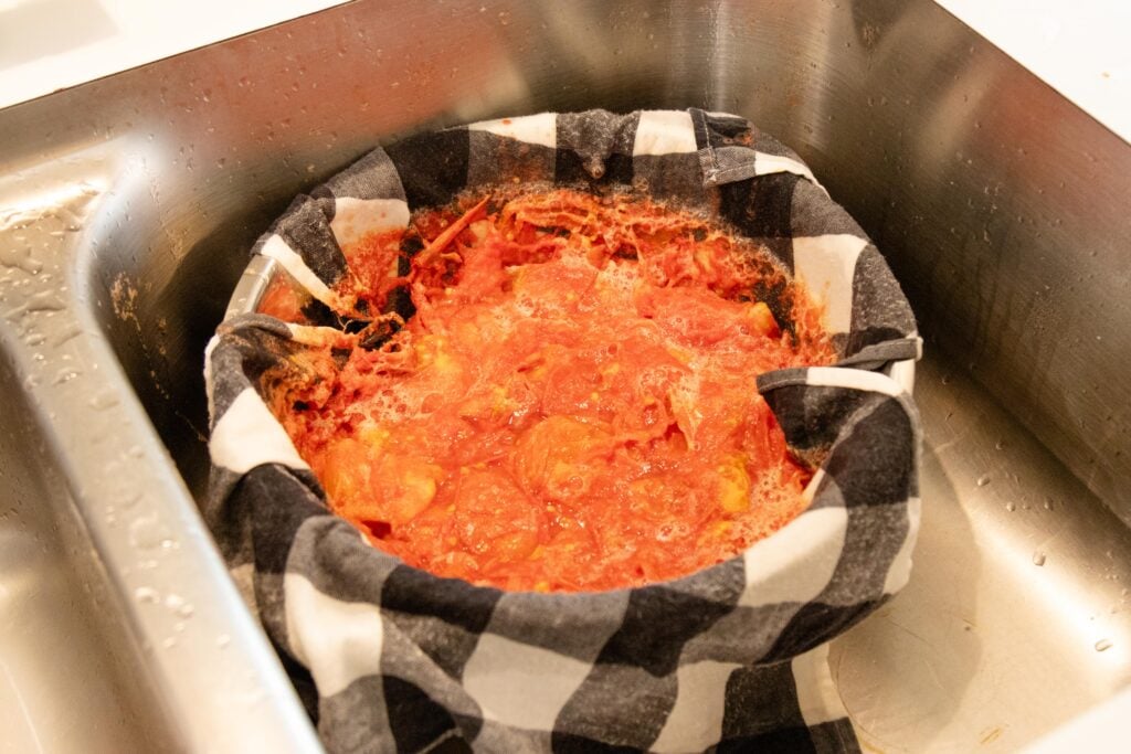 cooked tomatoes in the towel lined colander