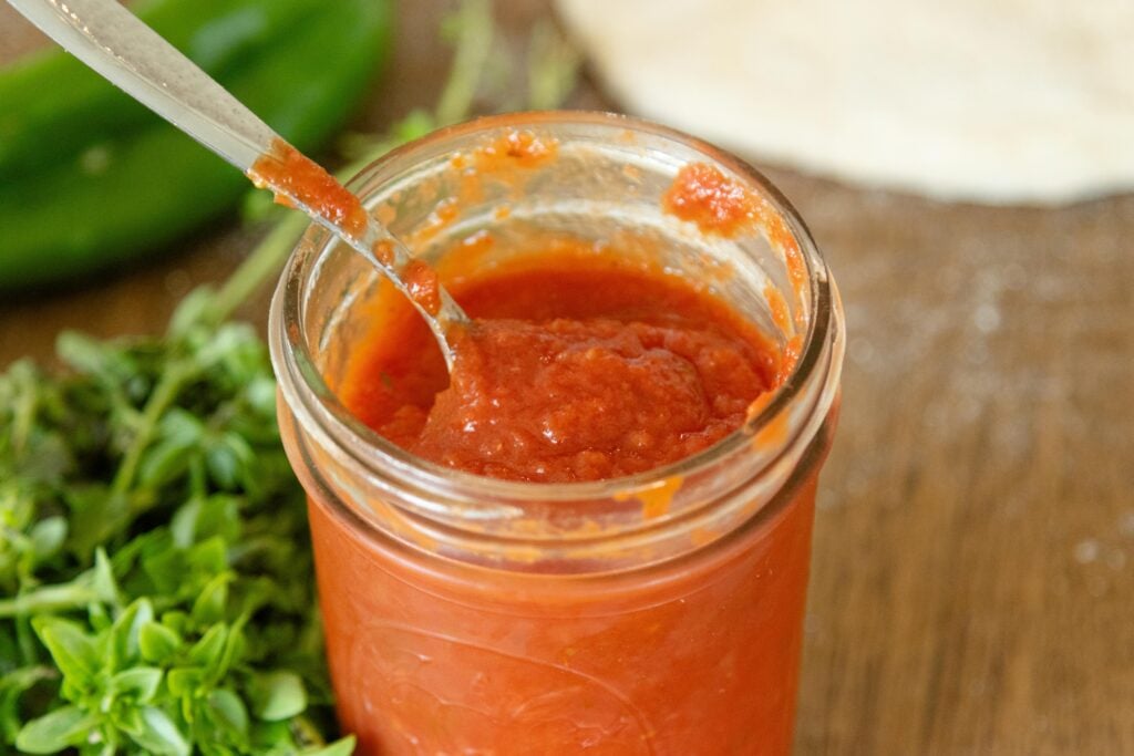 spoon scooping pizza sauce from a jar