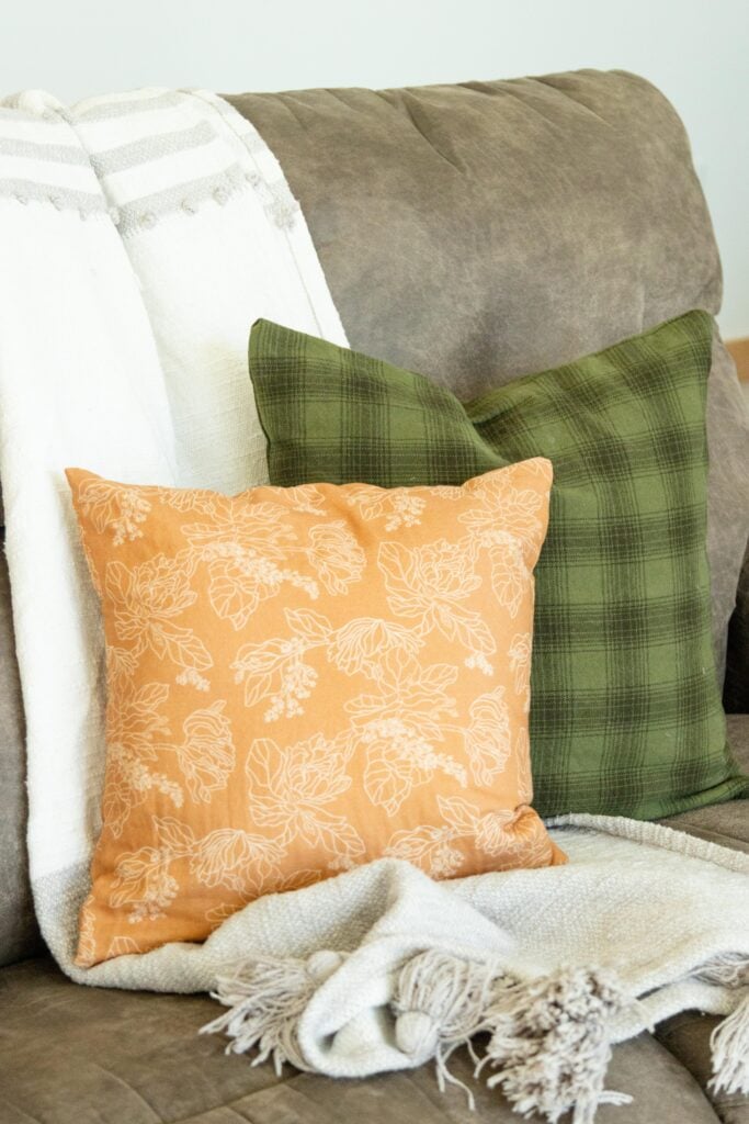 two pillows on a couch with a throw blanket