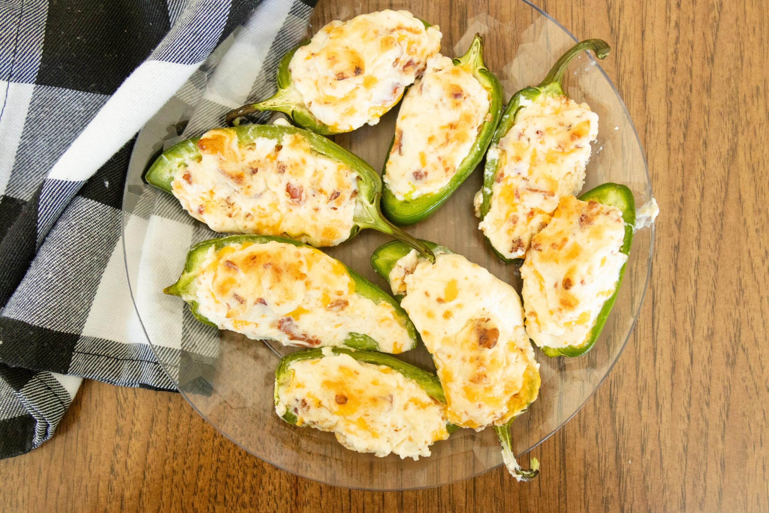 a plate full of jalapeno poppers on the table beside a checkered napkin