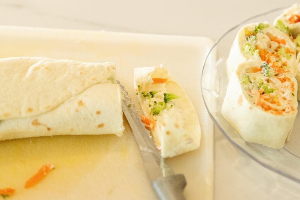 slicing the pinwheels on a cutting board