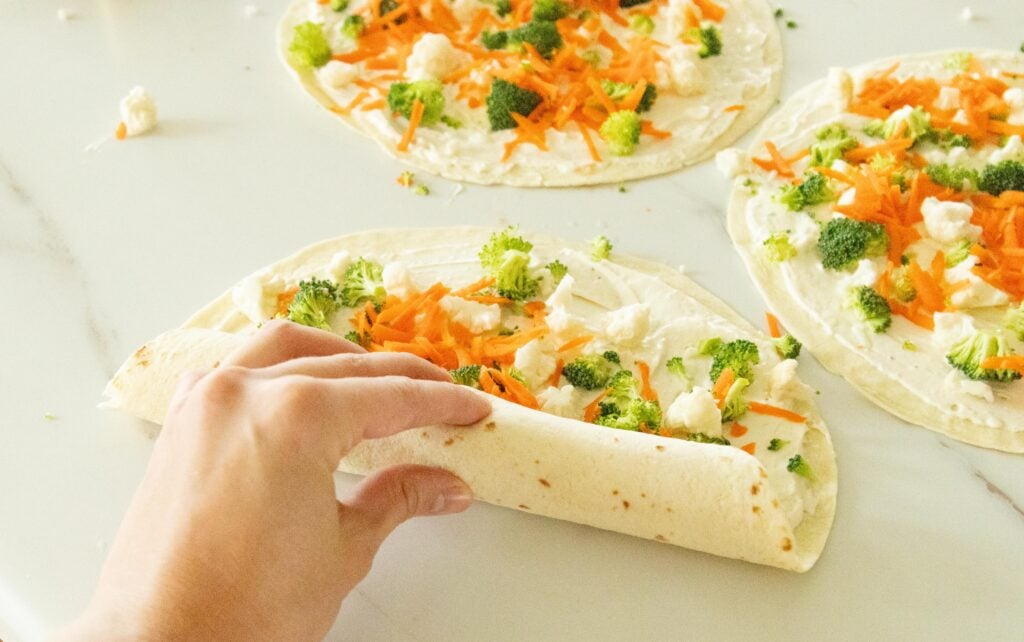 hand rolling up the tortilla pinwheels