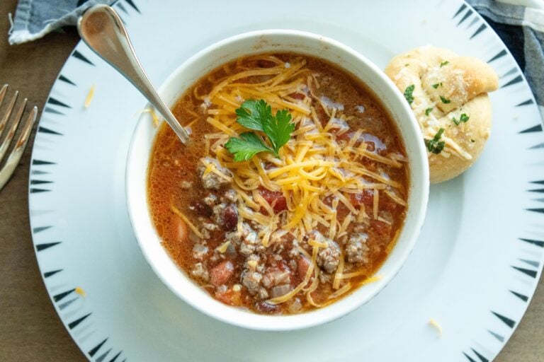 a bowl of chili soup setting on a white plate