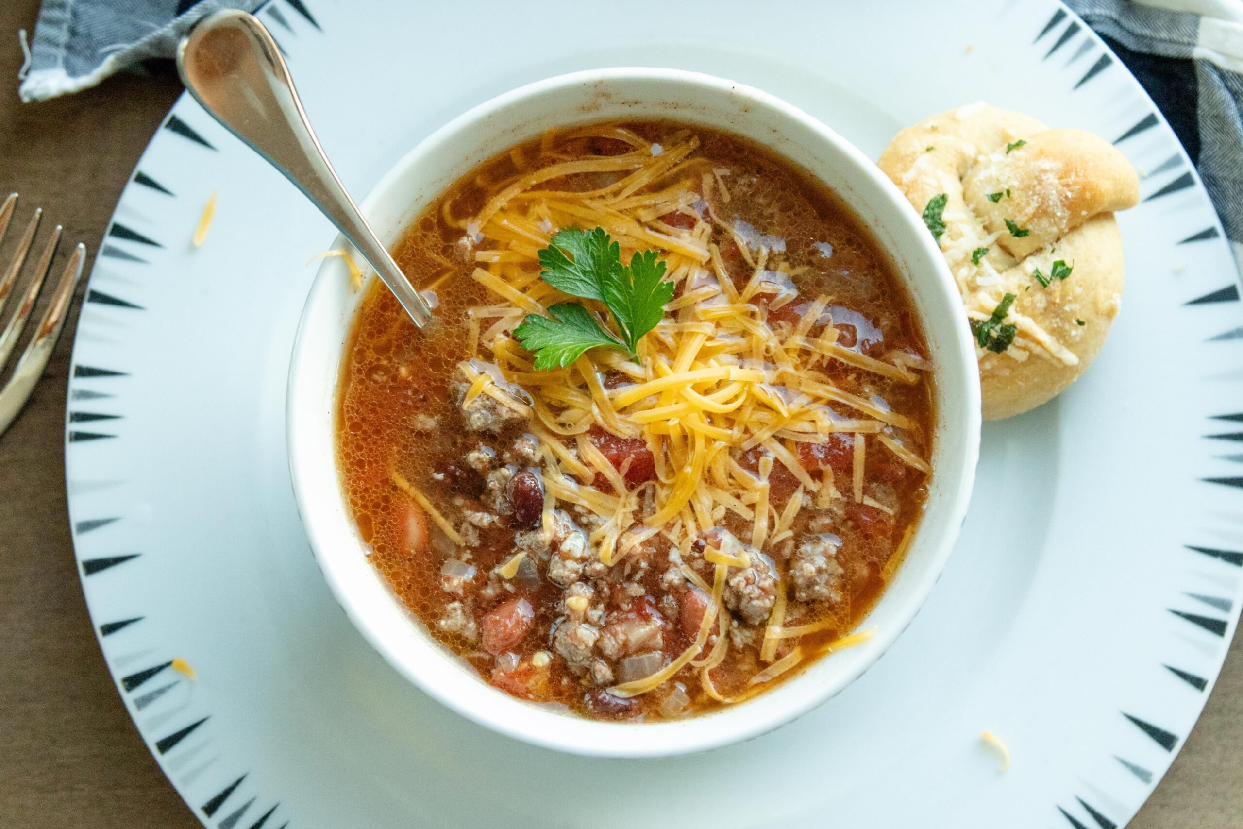 a bowl of chili soup setting on a white plate