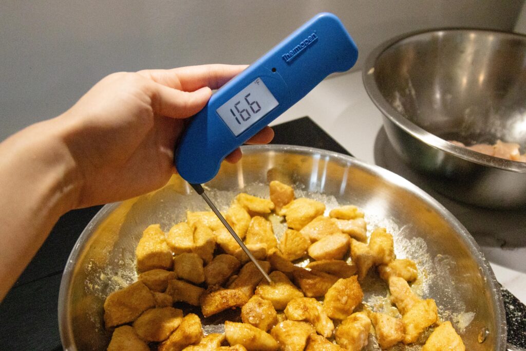 testing the internal temperature of the chicken with a meat thermometer