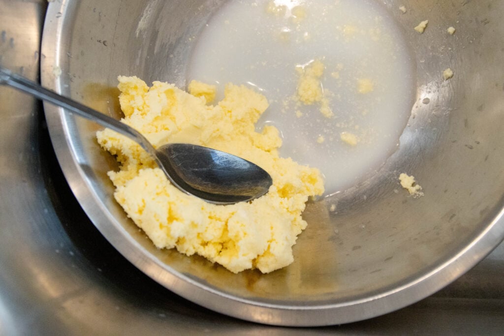 pressing the buttermilk out of the butter in a mixing bowl