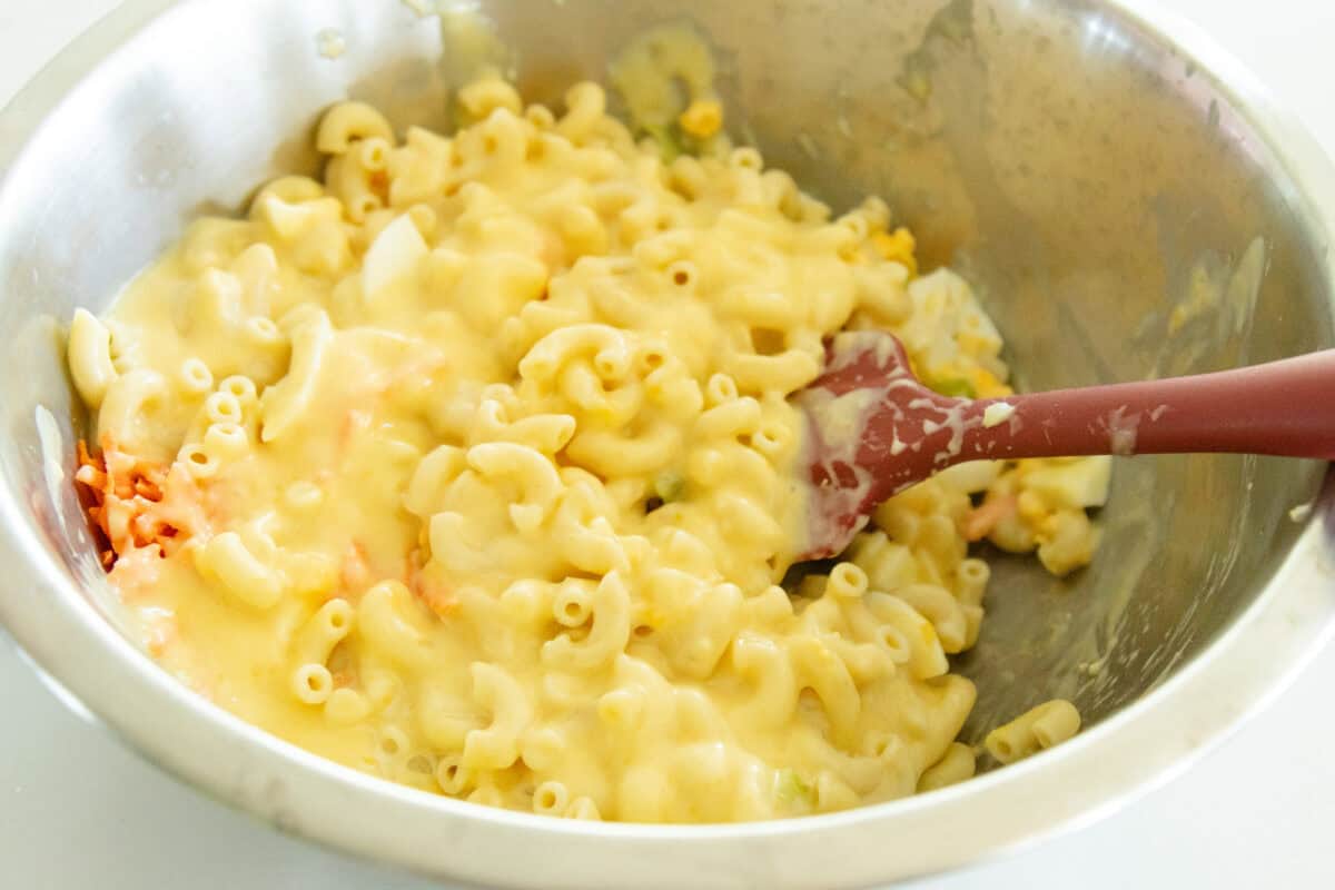 tossing the macaroni salad together with the dressing in a bowl