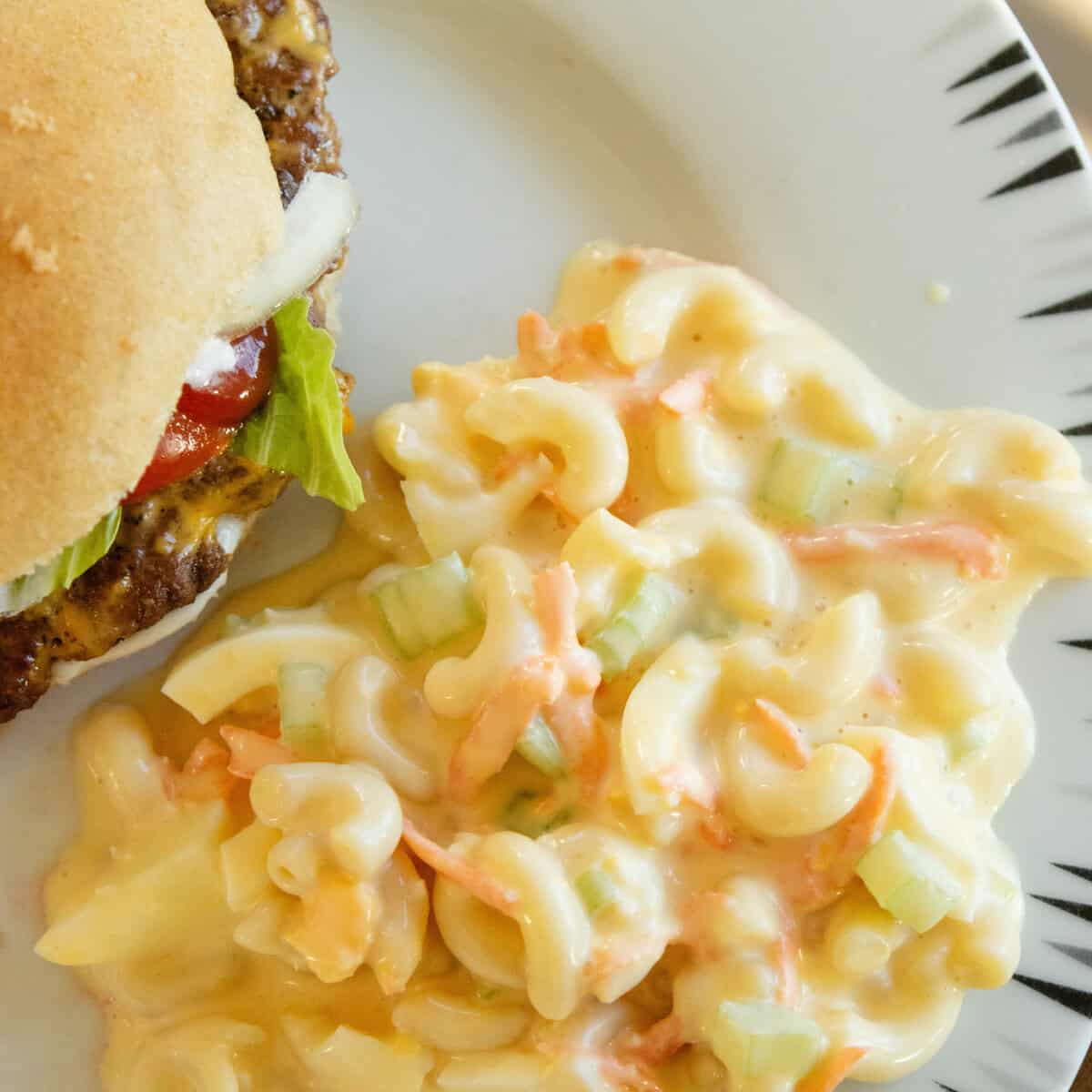 a serving of macaroni salad on a plate with a burger