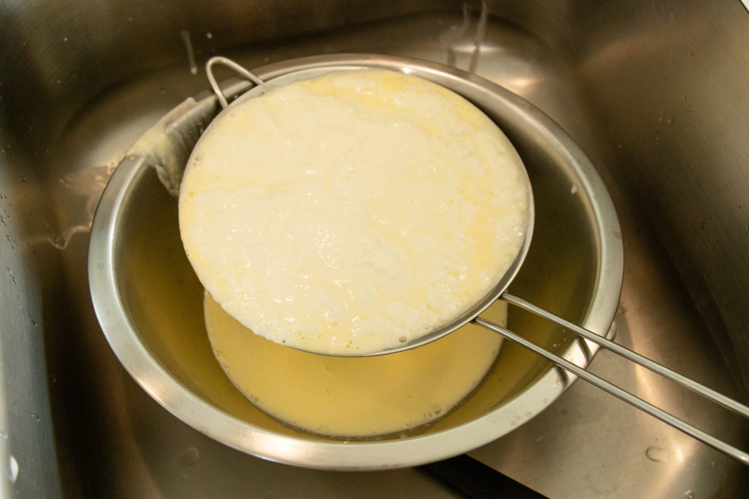 straining the yogurt in a strainer in the sink