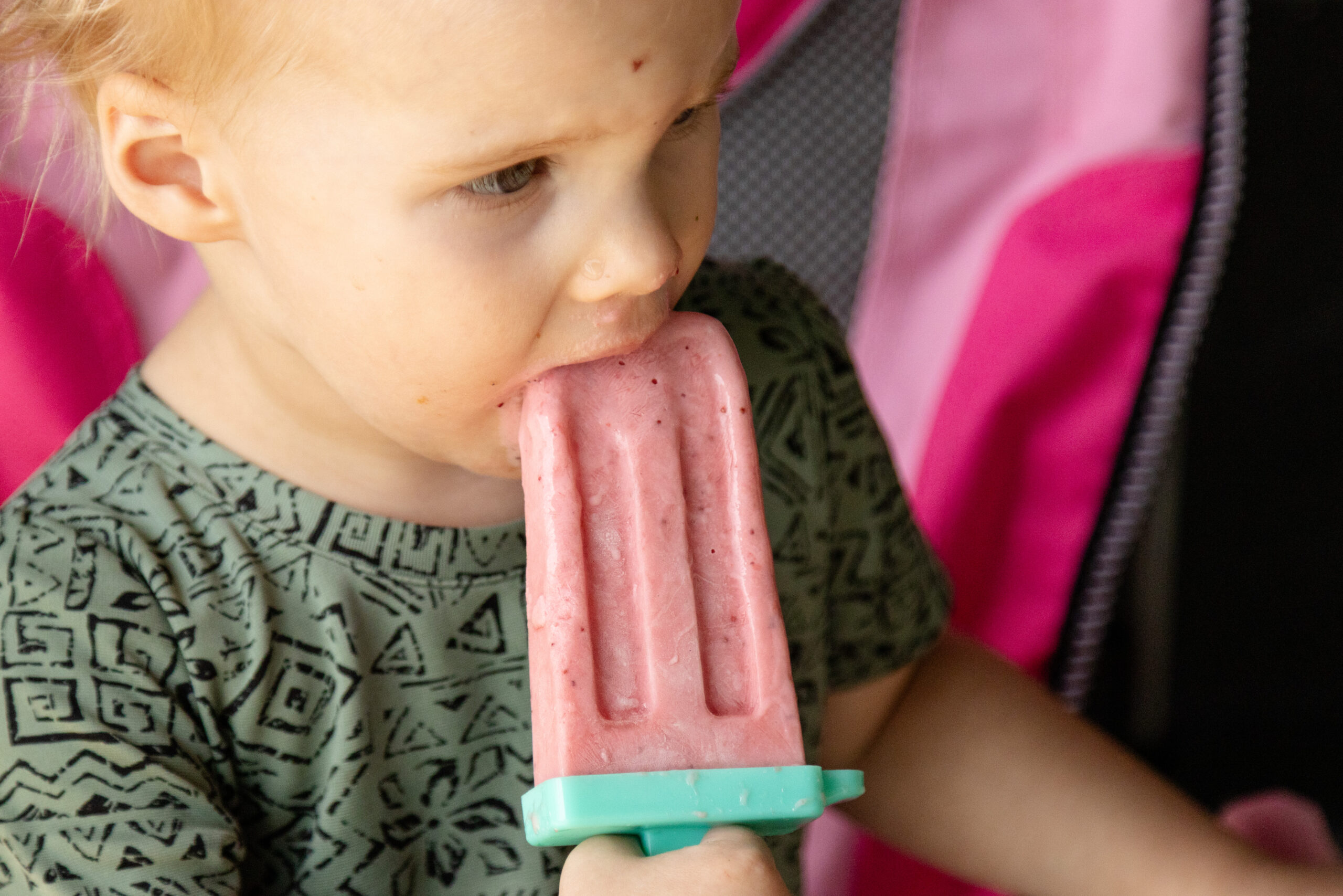 toddler licking a strawberry yogurt popsicle
