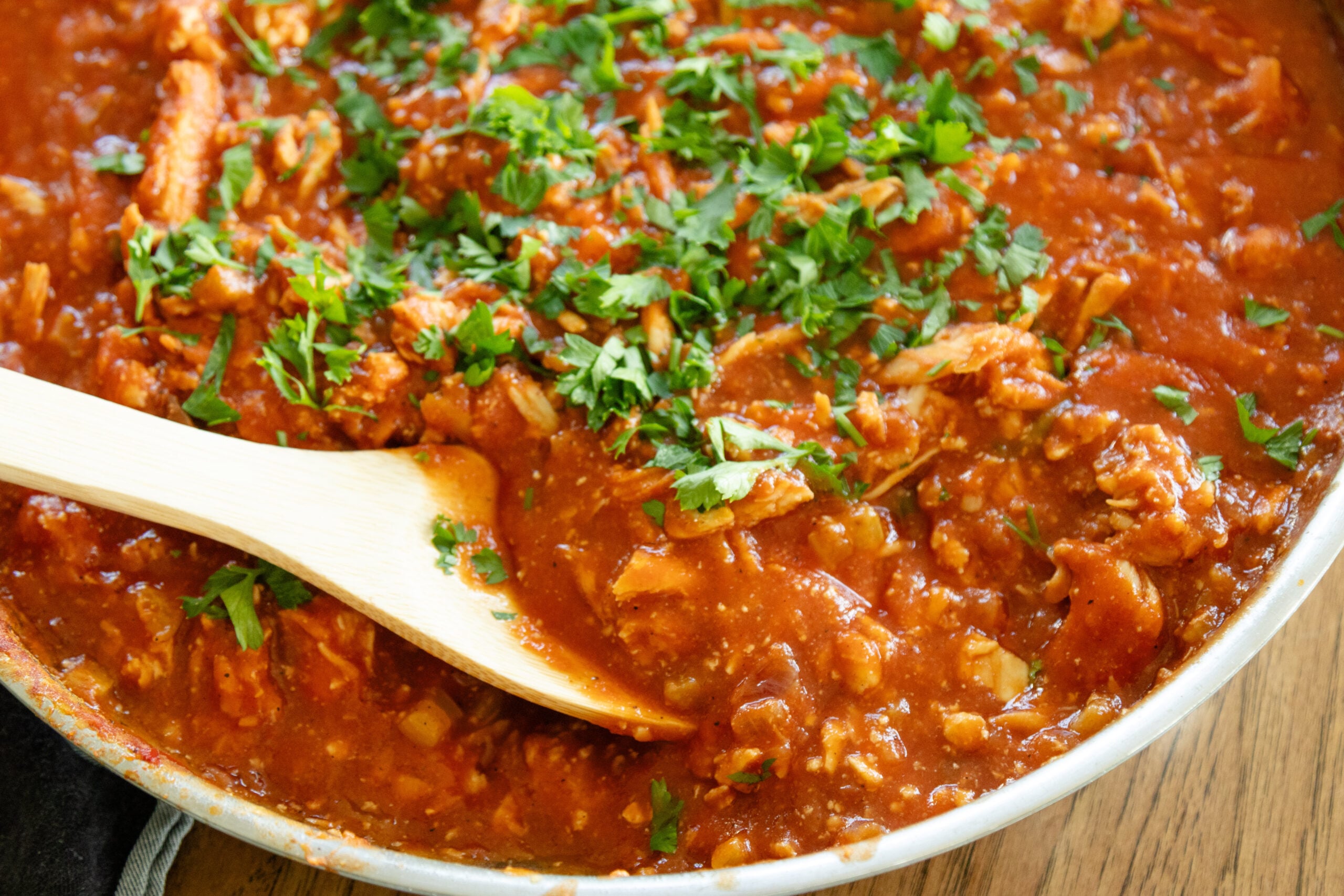 wooden spoon scooping chicken creole out of the pan