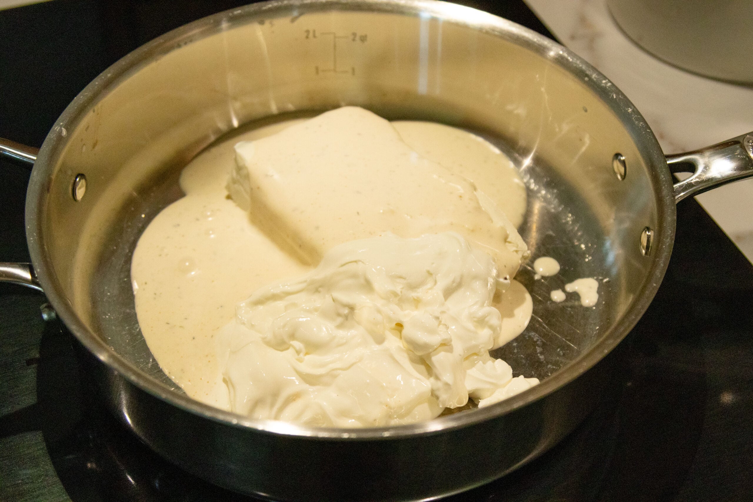 ranch cream cheese and sour cream melting in a saucepan
